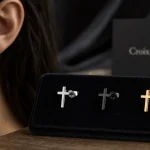 Boucle d'oreil croix en acier noirci et doré, fermoir à puce, gros plan