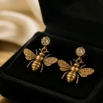 Boucles d oreilles abeilles dorées, gros plan sur écrin velours noir
