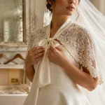 Veste mariée en dentelle sur robe de mariée ivoire, épaules couvertes sans cacher la robe